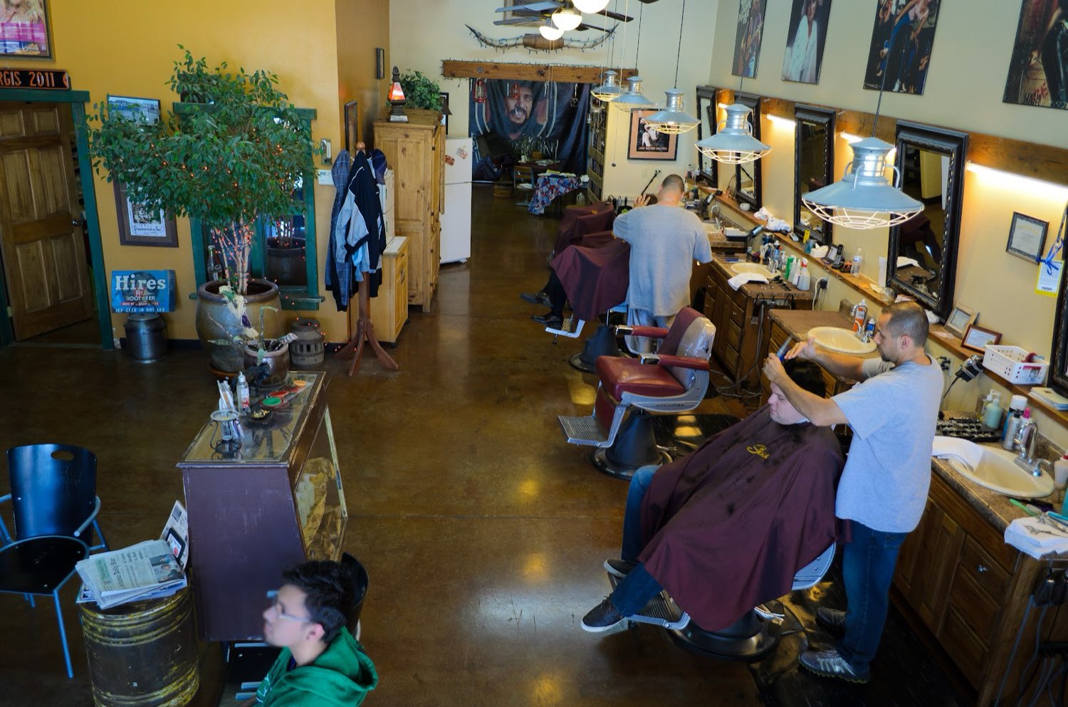 The length of the shop toward the front door, with a vintage root-beer sign, potted plants and framed country posters.